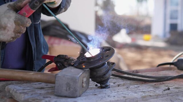 Closeup Torch Brazing Metal Flange. Fabricator Heating Flange With Precise Flame, Acetylene And Oxygen Stream Focused On Joint, Protective Gloves And Bench Clamp Hold Workpiece While Molten
