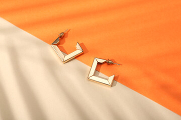 Naklejka premium Beautiful golden earrings on colorful background