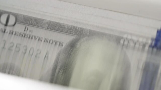 Close up automatic currency counter machine processing stack hundred dollar bills. High speed banking equipment counting American cash money. Financial technology business accounting wealth management
