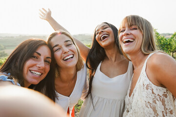 Fototapeta premium Group of female friends having fun at summer event in countryside with vineyards in background - Summer vacation, UGC content, party and travel concept - Main focus on center latin woman face