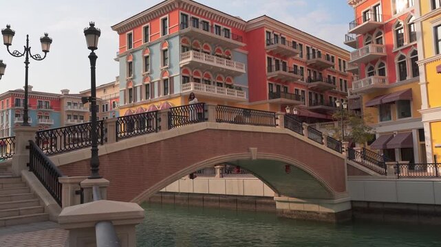 Doha, Qatar - 20th january, 2026: Woman traveler walk on bridge in Qanat Quartier Pearl Qatar colorful Venice style architecture with canals bridges luxury waterfront lifestyle travel destination