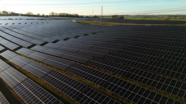Aerial view of the expansive Tye Lane Solar Farm, where rows of dark solar panels contrast with the surrounding landscape, Ipswich, United Kingdom.