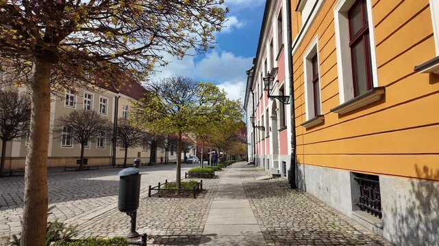 Walking through scenic Katedralna street in Ostrow Tumski, Wroclaw, spring view of historic architecture and blooming trees, tourist path in the oldest part of the city, sunny day, stroll.