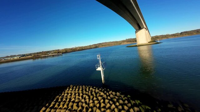 Aerial FPV view of a serene beach with the tide out, revealing the damp sand and the distant horizon under a clear blue sky, Ipswich, England, United Kingdom.
