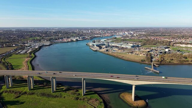 Aerial view of the Orwell Bridge over tranquil blue waters, contrasting with the green landscapes and industrial areas lining the banks, Ipswich, England, United Kingdom.