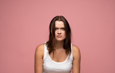 Obraz premium Young woman feeling frustrated and annoyed with messy, tangled hair, making a grimace on a pink background