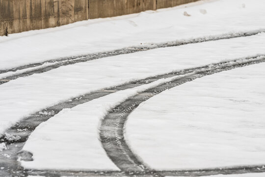Curved tire tracks carved into fresh snow creating abstract winter pattern.