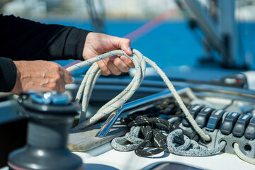 Hands coiling rope on sailing yacht deck © Nazareno