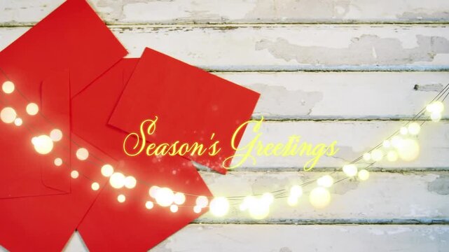 Animation of text, season's greetings, in yellow, over string lights and red envelopes