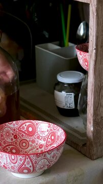 Series shows a woman preparing kombucha in a rural Ukrainian home. She rinses the tea mushroom, cleans jars, pours fermented drink into bottles, highlighting traditional lifestyle and health benefits.