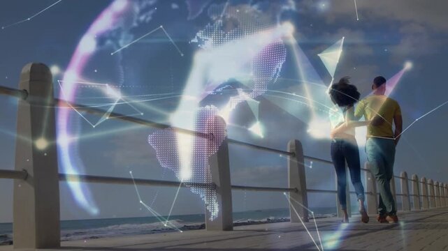 Couple walking seafront, movement sparking network forming holographic globe visualizing technology