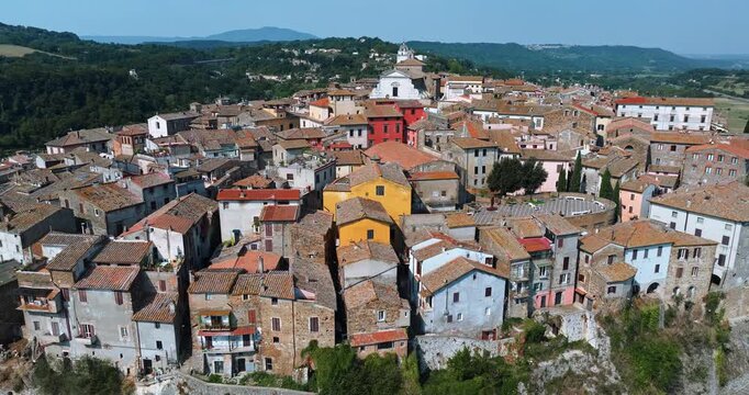 Aerial drone flight Orte Italy summer. Panoramic view medieval town built tuff cliff. Traditional italian houses tiled roofs surrounded lush green trees valley. Historical lazio architecture travel co