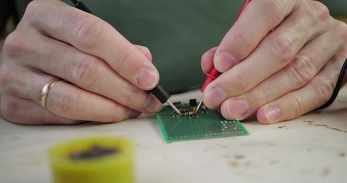 Hands work on circuit board using multimeter. Close-up shows precision in electronics repair. Focus on circuit components and tools for efficient troubleshooting. Perfect for technology enthusiasts.