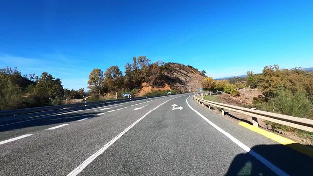 Exciting road trip driving through empty countryside asphalt under bright summer sky, adventure concept. POV from vehicle moving fast toward destination surrounded by nature and scenic rural landscape