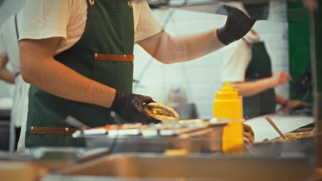 In bustling street eatery, skilled chefs efficiently cook prepare orders for waiting guests, expertly assembling burgers and freshly baking pitas for take-out food delivery and quick dine-in service