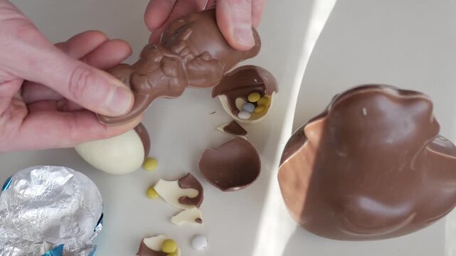 Hands unwrapping Easter chocolate egg with candy inside