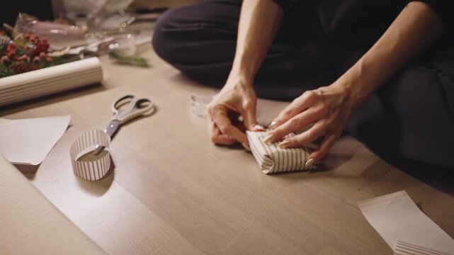 Woman Wrapping Christmas Gifts On The Wooden Floor. - closeup shot