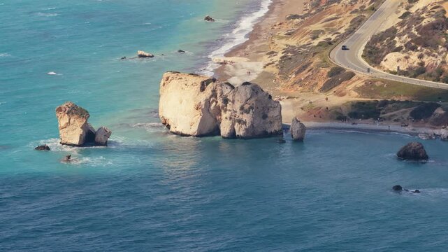 Aerial drone view of Aphrodite's Rock with turquoise sea and nearby coastal road, one of Cyprus' most famous natural landmarks