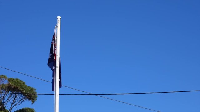 Australian flag on pole against clear blue sky, Tathra, New South Wales, Australia.