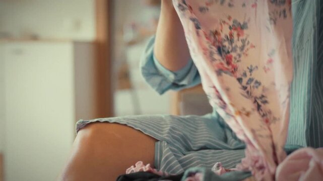 A diligent young housewife meticulously folds freshly laundered clothes at home, methodically sorting and creasing each item to preserve a sense of organization and tidiness in her domestic space