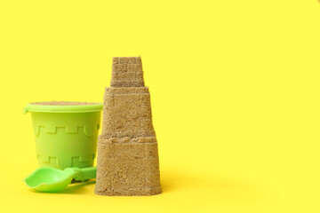 Beautiful sand castle with toy shovel and bucket on yellow background © Pixel-Shot