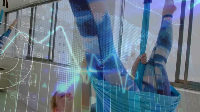 Female yoga student shifting weight into aerial silk and inverting for core strength in studio