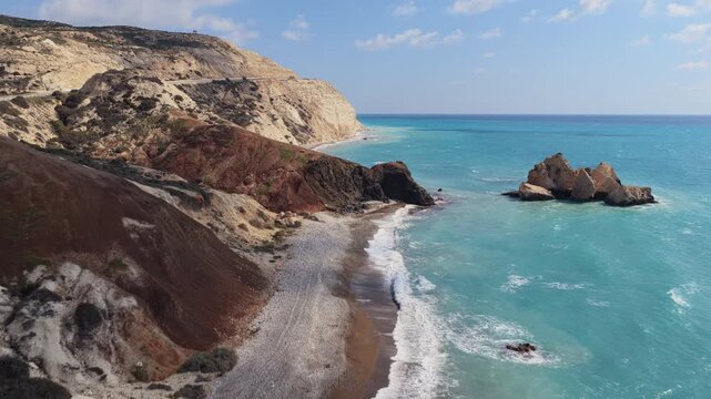 Aerial drone view of rugged cliffs and rocky beach with waves washing onto the shore in Cyprus