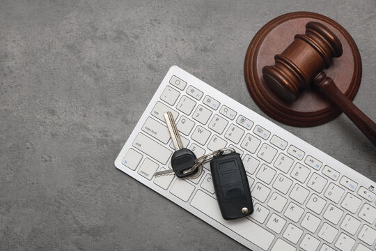 Car key with computer keyboard and auction gavel on dark background
