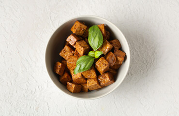 Fototapeta premium Bowl with pieces of fried tofu cheese and basil on white background