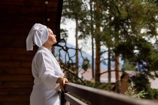 a woman in a white robe and a towel on her head, with mountains in the background, in a hotel