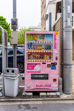 Kyoto, Japan - April 20, 2025 Pink vending machine with colorful drinks on an urban street with cars and buildings