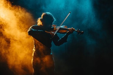 Fototapeta premium Silhouette of young male violinist in dramatic lighting
