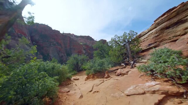 A scenic view from the Canyon Overlook Trail in Zion National Park, Utah, USA. The footage captures the dramatic red rock formations and towering cliffs of the canyon landscape on a bright, sunny day.