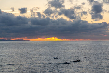 Colorful sunrise over the Cantabrian Sea with a traditional Basque rowing boat training near the coast of San Sebastian in the Basque Country, Spain.