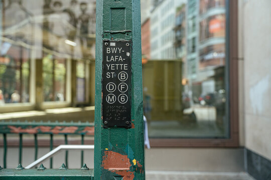 New York City, New York, USA - 08.03.2024: A Broadway Lafayette Street subway sign displays the B, D, F, M, and 6 train lines in New York City. The green station entrance and urban background