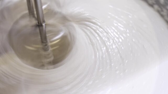 Mixing sugar and egg whites to create meringue and marshmallow cream for desserts in a home kitchen