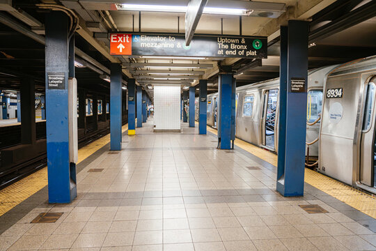 New York City, New York, USA - 08.03.2024: New York City subway platform at Broadway Lafayette Street station with train and exit signage. Underground urban transportation hub with blue columns, tiled