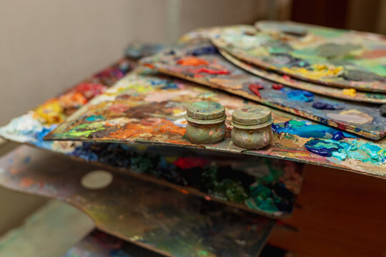 An old palette with oil paints in the artist's studio. Painted background created by a creative person. 