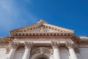 Fototapeta premium Neoclassical facade with ornate corinthian columns and sculpted pediment against blue sky showing architectural detail and classical stonework on a grand historic building