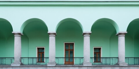 Fototapeta premium Mint arcade balcony columns wooden doors repeating arches across pastel facade with wrought railing
