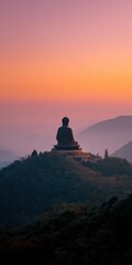 Fototapeta premium Buddha male asian adult statue on hilltop at sunrise overlooking layered mountains and mist with warm pink and orange sky