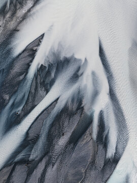 Aerial view of braided river patterns carve through the landscape, a dance of light and shadow on the glacial outwash plains, Lake Tekapo, New Zealand.