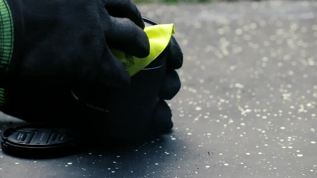 Gloved hand cleaning camera lens with yellow microfiber cloth photography gear maintenance