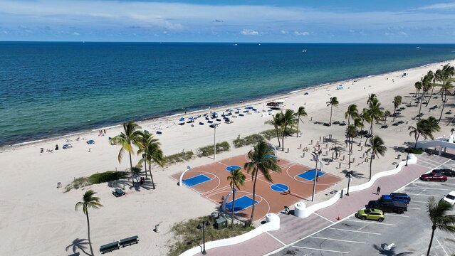 Aerial view of a basketball court on the sand next to the beach with turquoise waters and palm trees, Fort Lauderdale, USA.