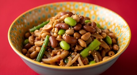 A colorful legume salad with edamame, kidney beans, and peanuts served in a vibrant patterned bowl on red.