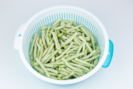 The fresh green vegetables in the vegetable washing basket, including green beans.