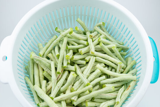 The fresh green vegetables in the vegetable washing basket, including green beans.