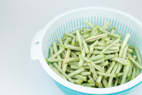 The fresh green vegetables in the vegetable washing basket, including green beans.