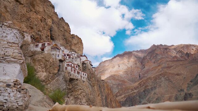 4k stable shot of the ancient Tibetan Buddhist Phuktal monastery of on a steep rocky hillside in the Zanskar region in Ladakh in the Indian Himalaya. Clouds in sky during summer day. Nature Landscape.