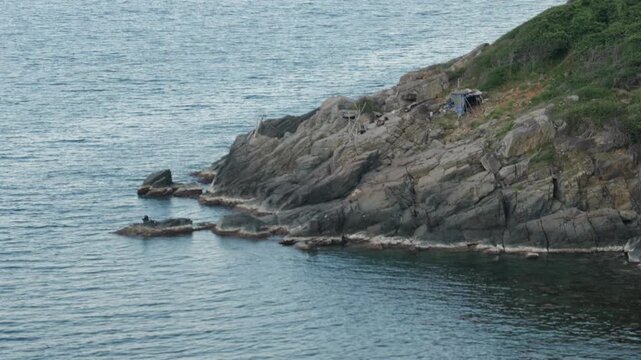 Lone survivalist living in a remote rocky coastal shelter by the sea, off-grid lifestyle
